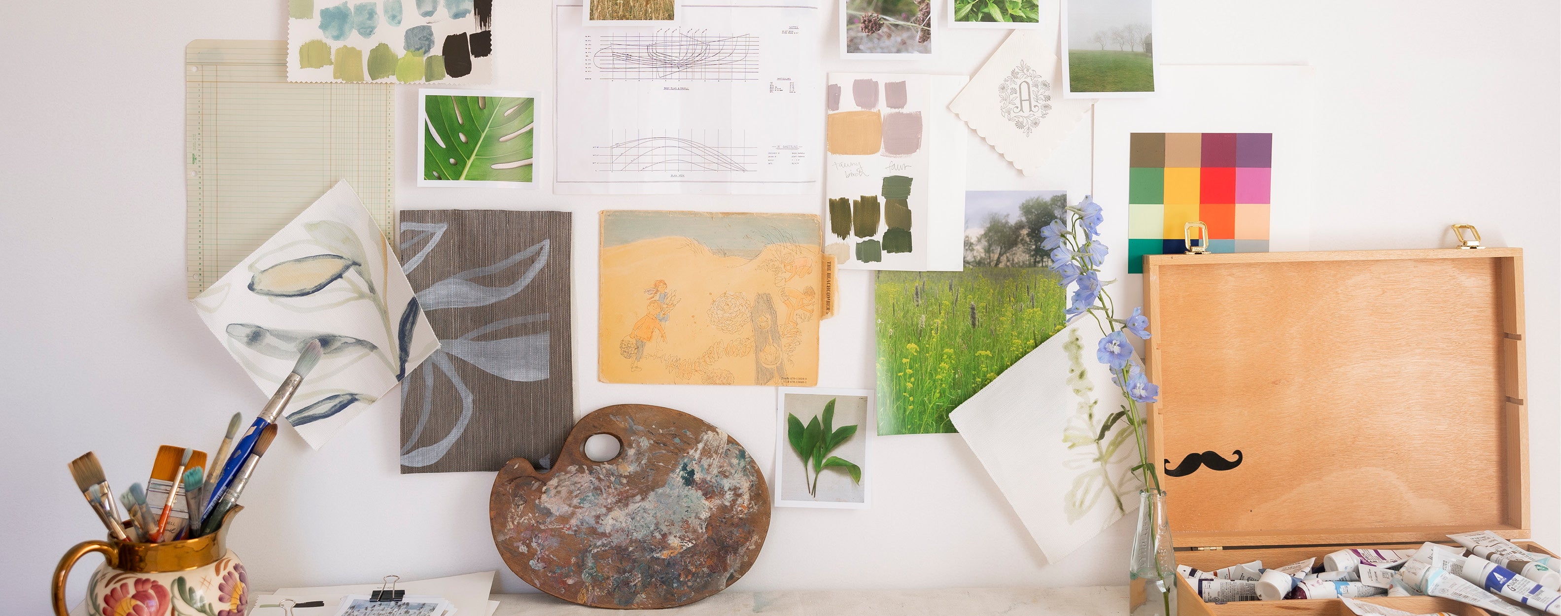 Collage of color swatches, art supplies, and a wooden box on a white surface.