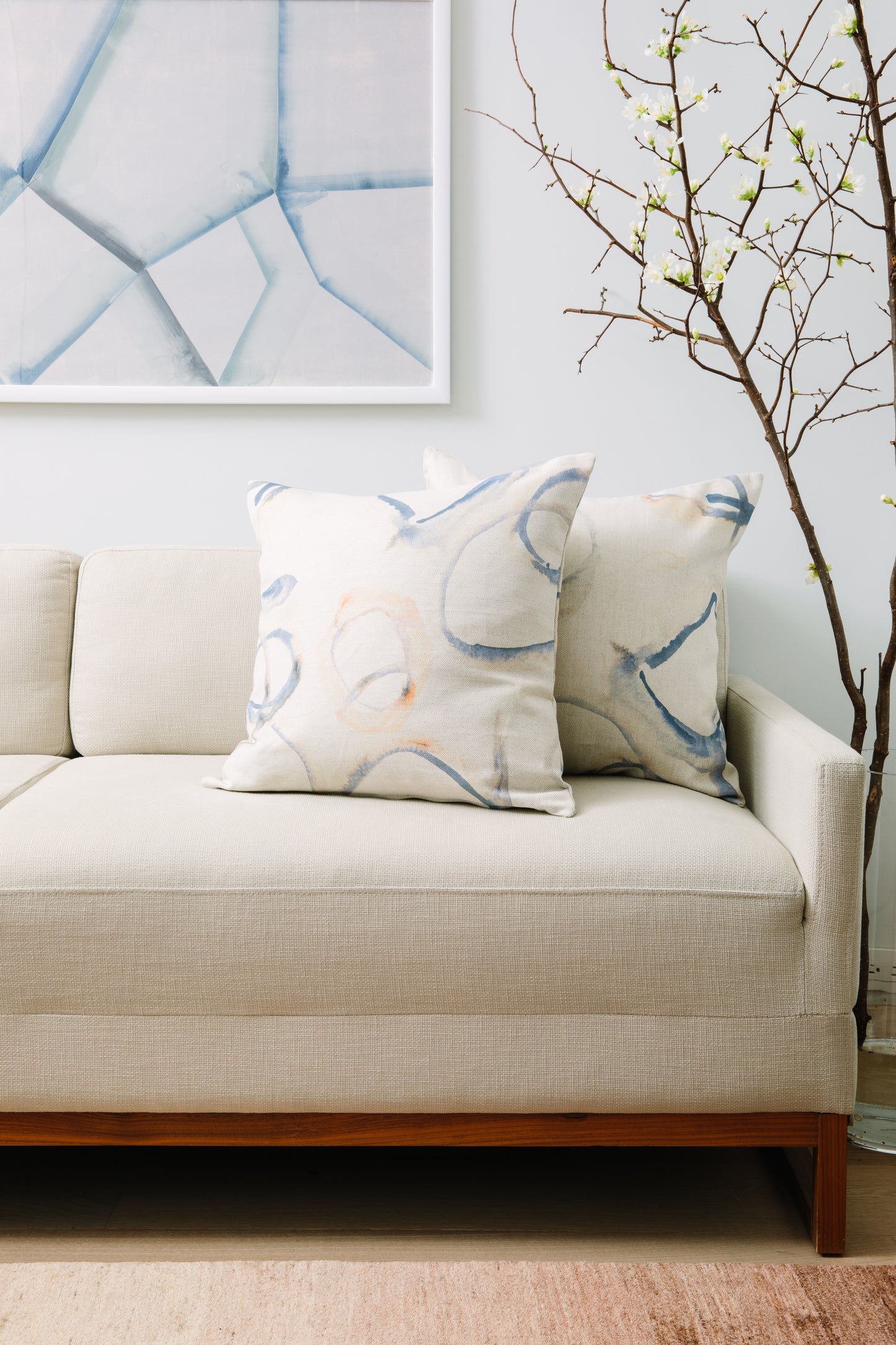 Beige sofa with decorative pillows and a abstract painting in a living room setting