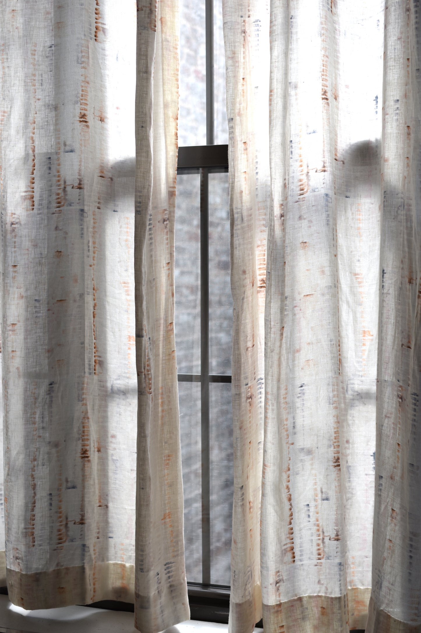 Sheer curtains with a subtle pattern in front of a window