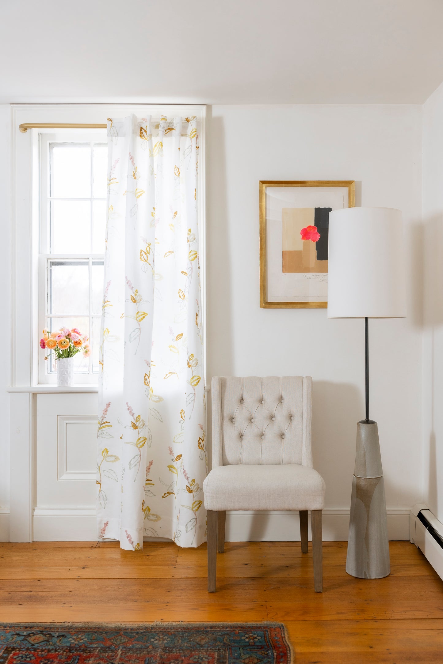 Living room with a chair, lamp, and framed picture on a white wall.