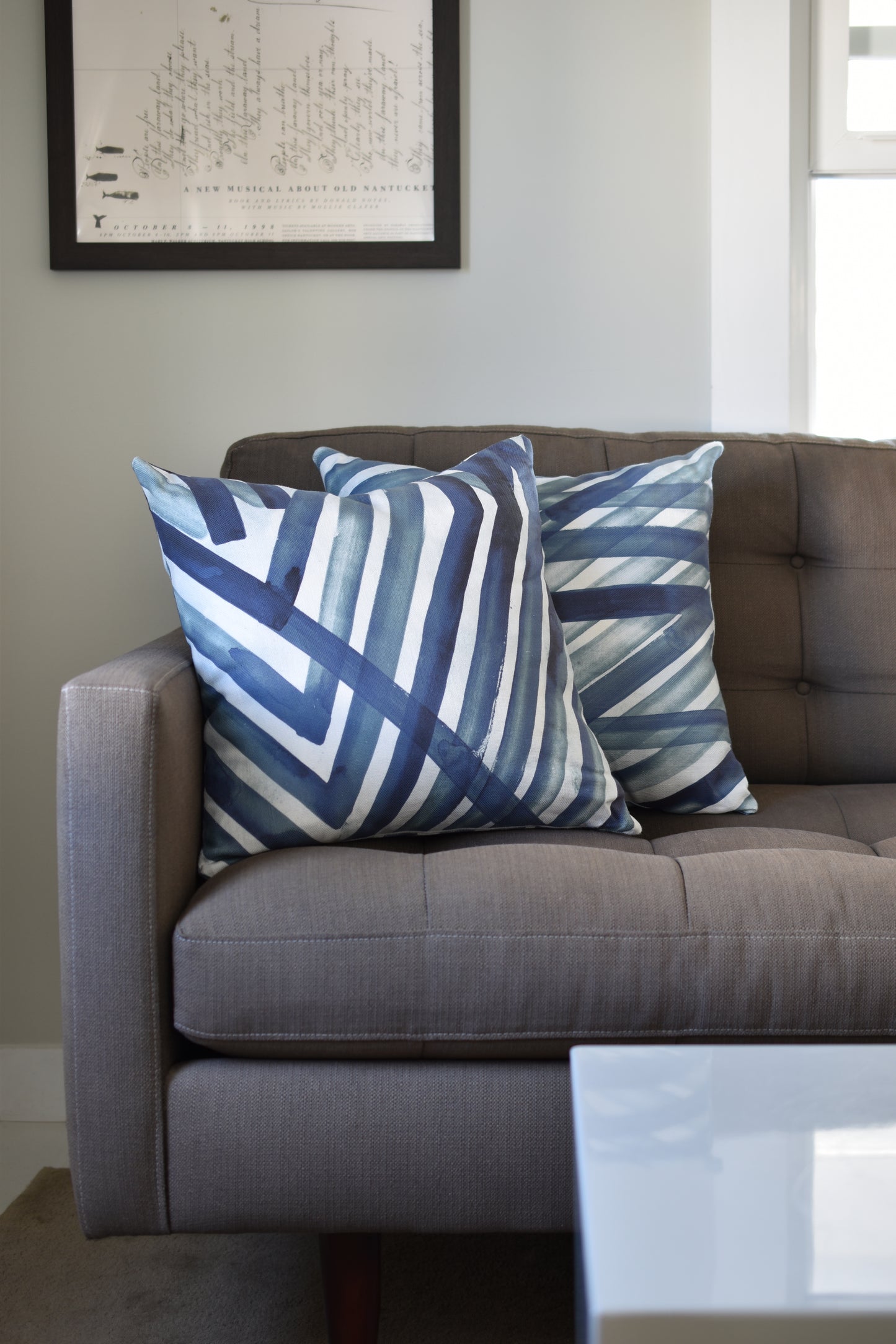 Gray sofa with blue and white striped cushions in a living room setting.