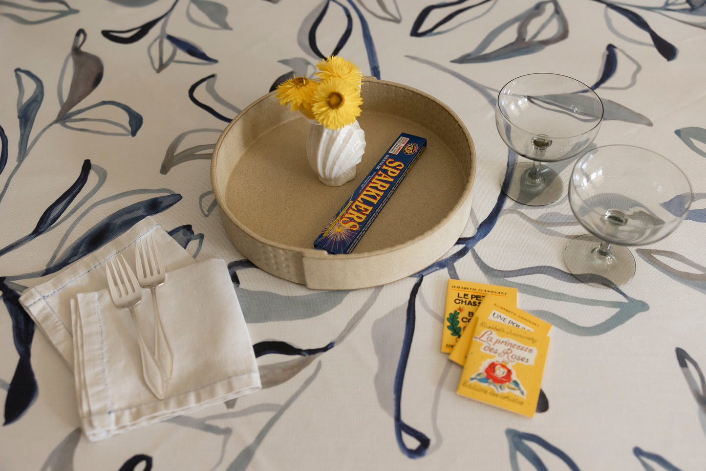 Table setting with a decorative plate, napkin, and small items on a patterned tablecloth.