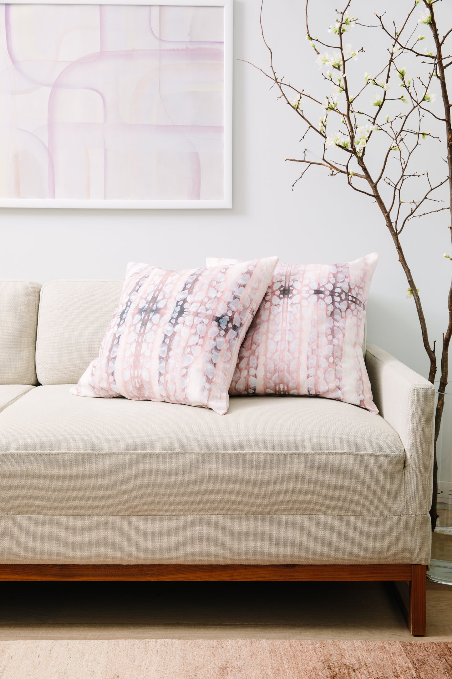 Beige sofa with pink floral cushions in a living room setting.