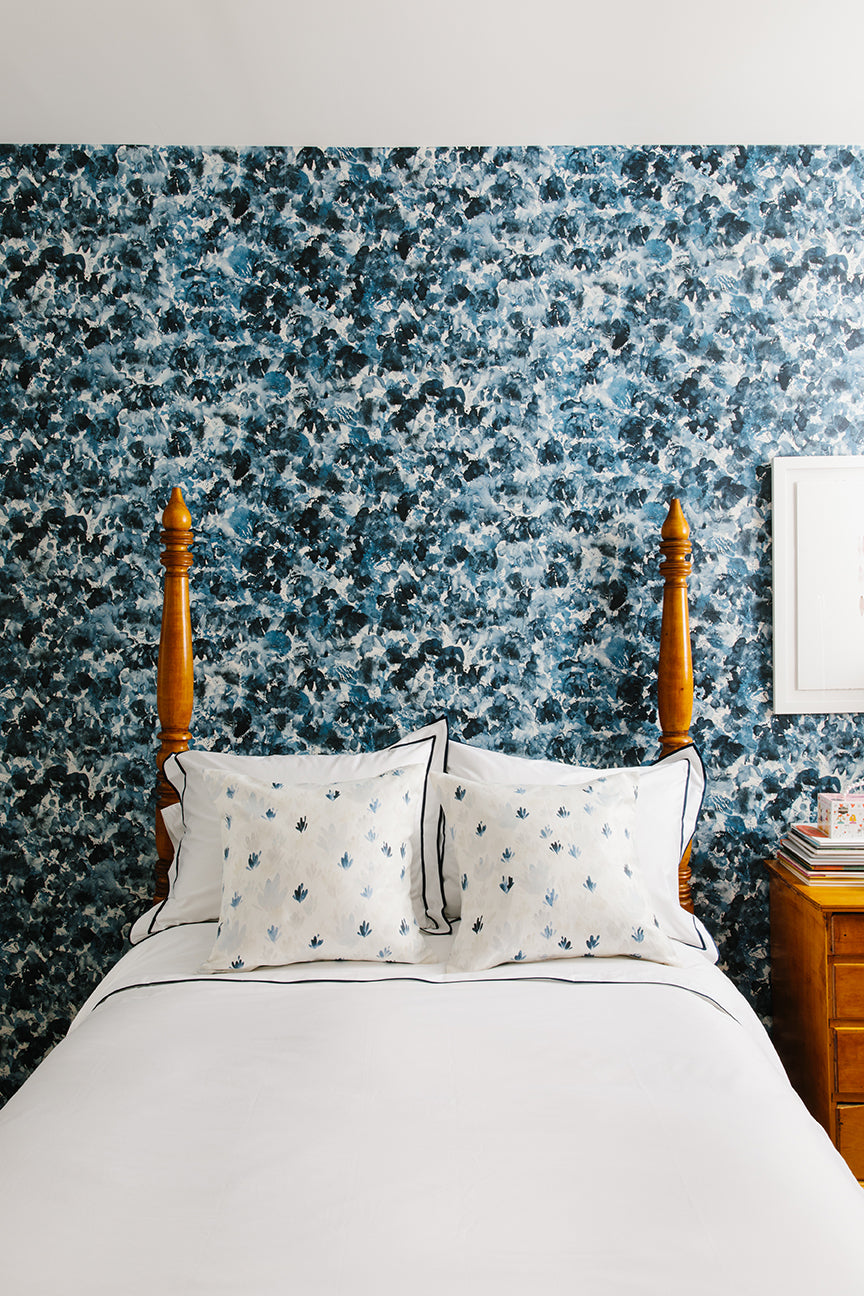 Bedroom with floral wallpaper, wooden headboard, and white bedding.