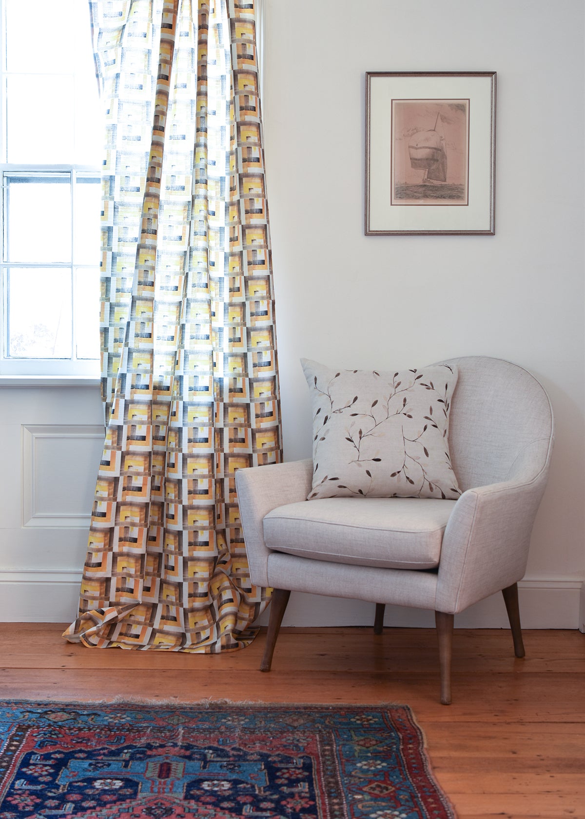 Living room with a chair, patterned curtains, and a rug.