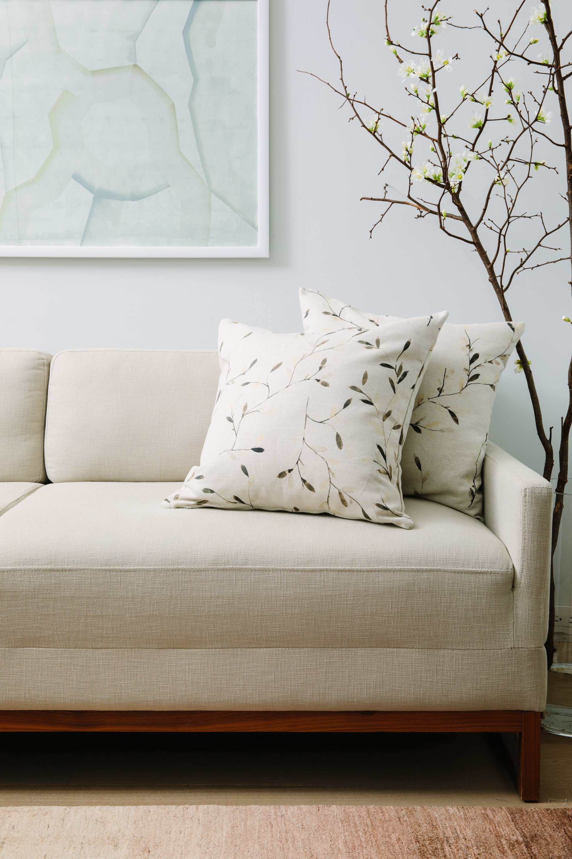 Beige sofa with decorative pillows and a plant in a room with light blue walls.
