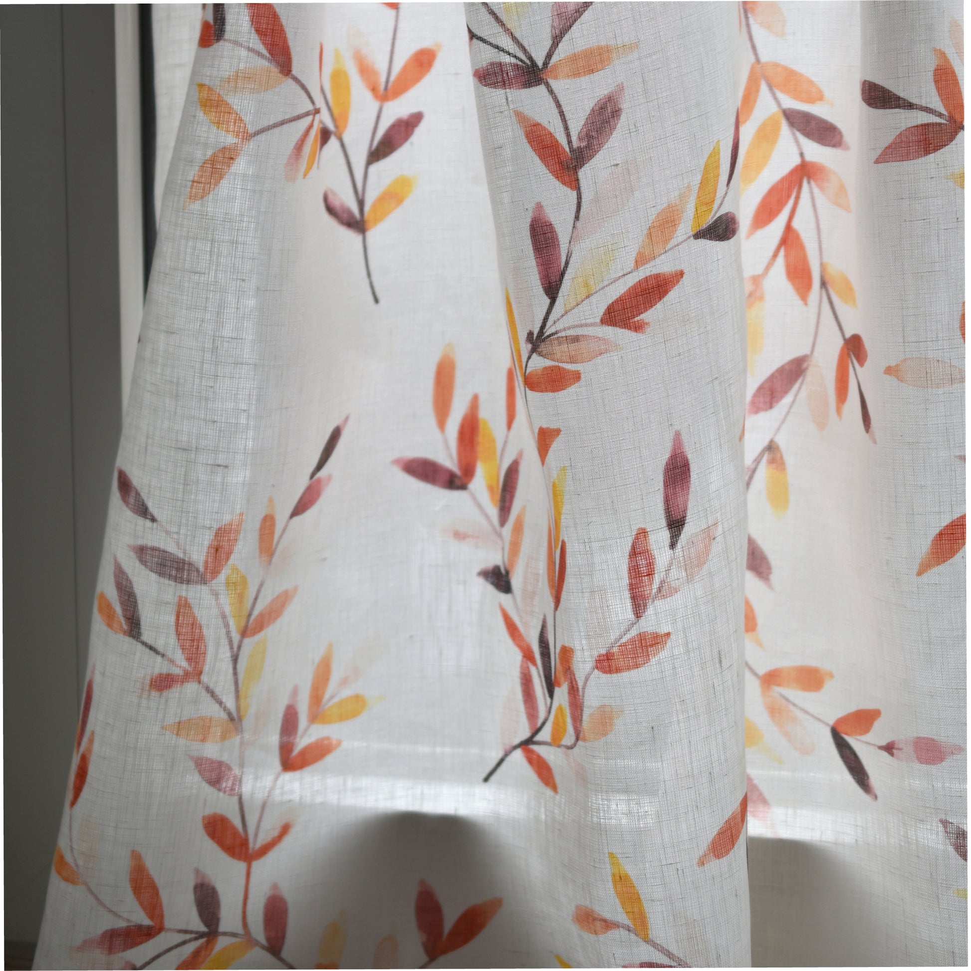 Sheer curtain with autumn leaf pattern on a white background