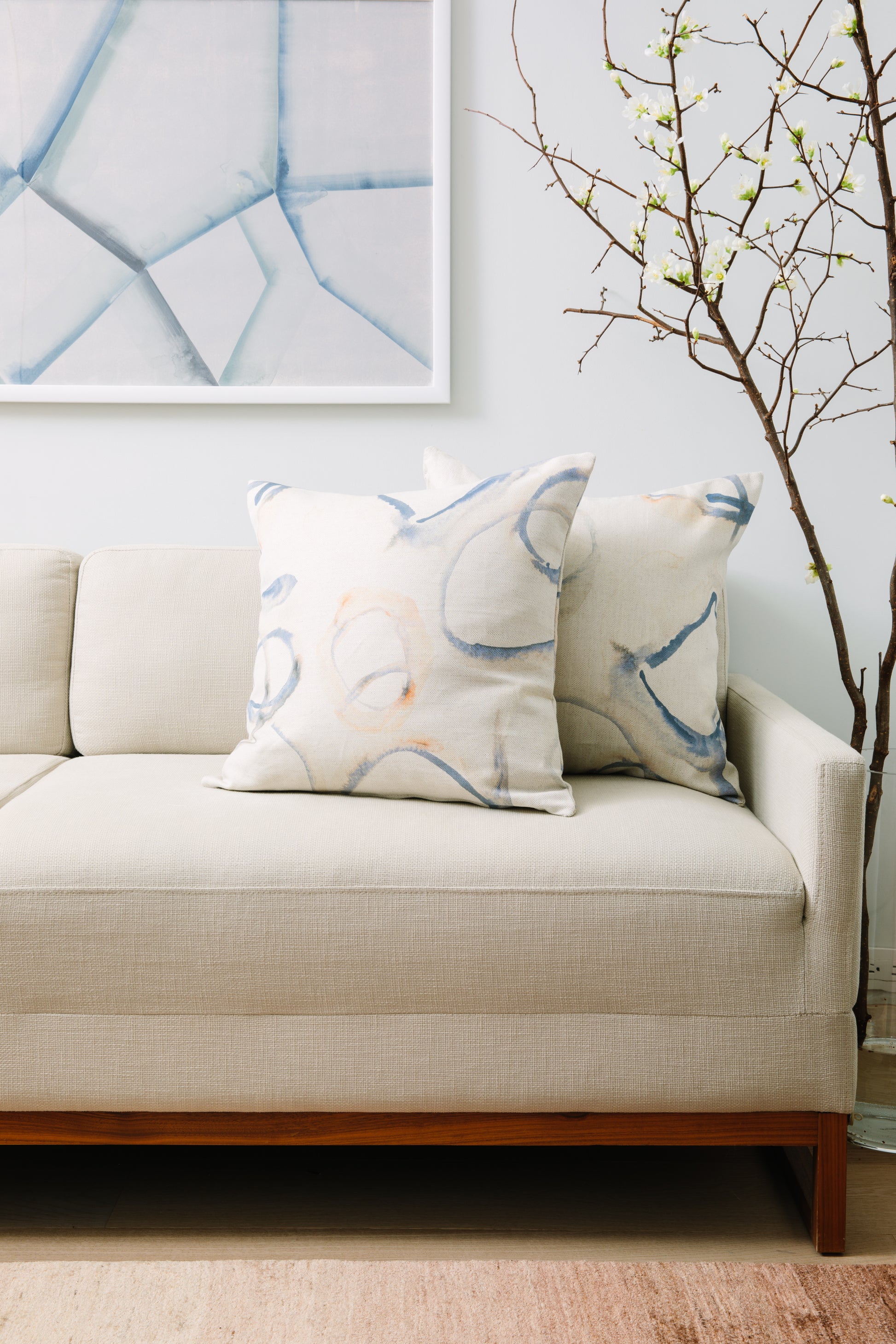 Beige sofa with decorative pillows and a abstract painting in a living room setting
