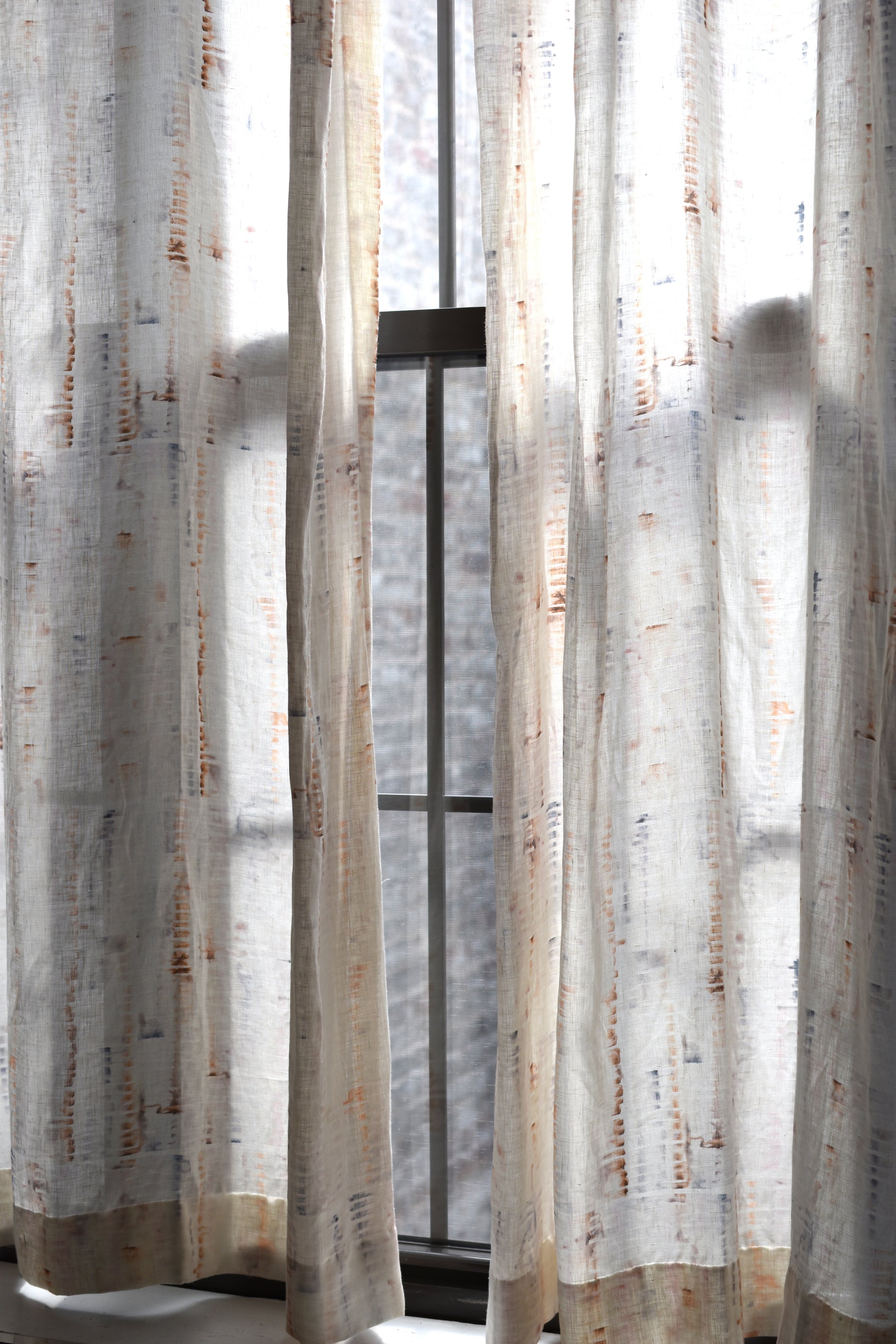 Sheer curtains with a subtle pattern in front of a window