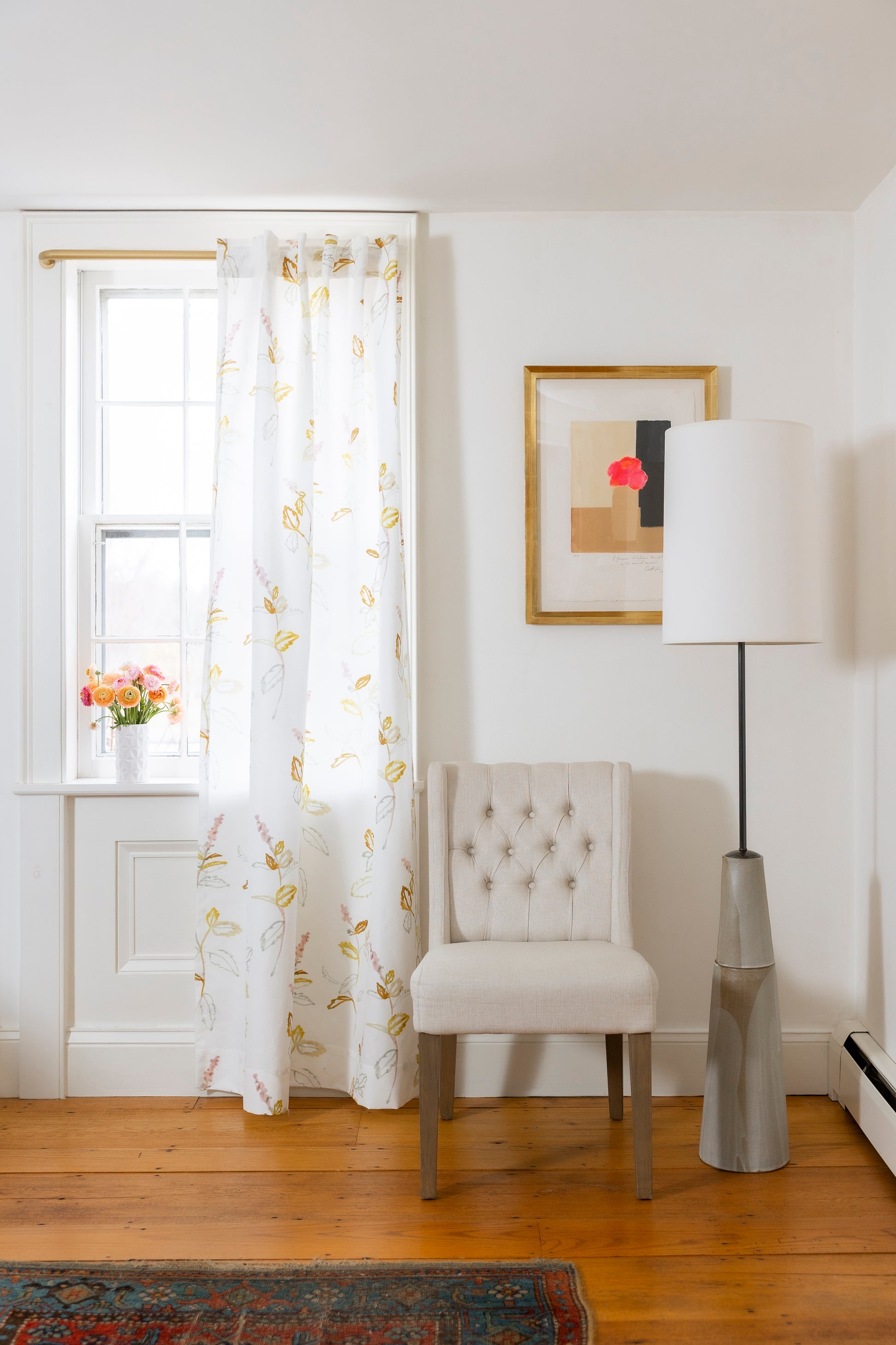 Living room with a chair, lamp, and framed picture on a white wall.