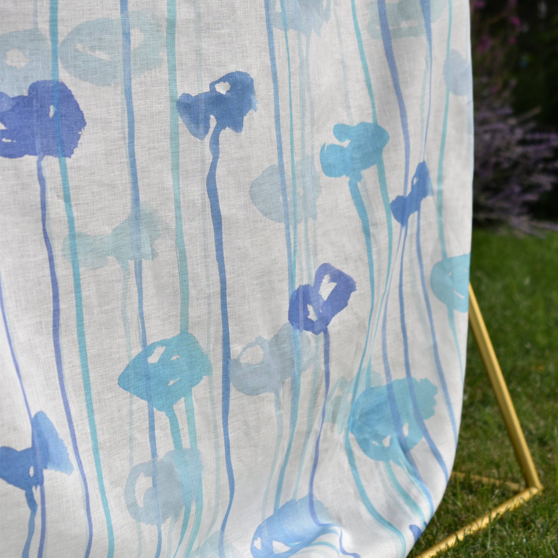 Blue floral pattern on a white fabric draped over a chair outdoors.