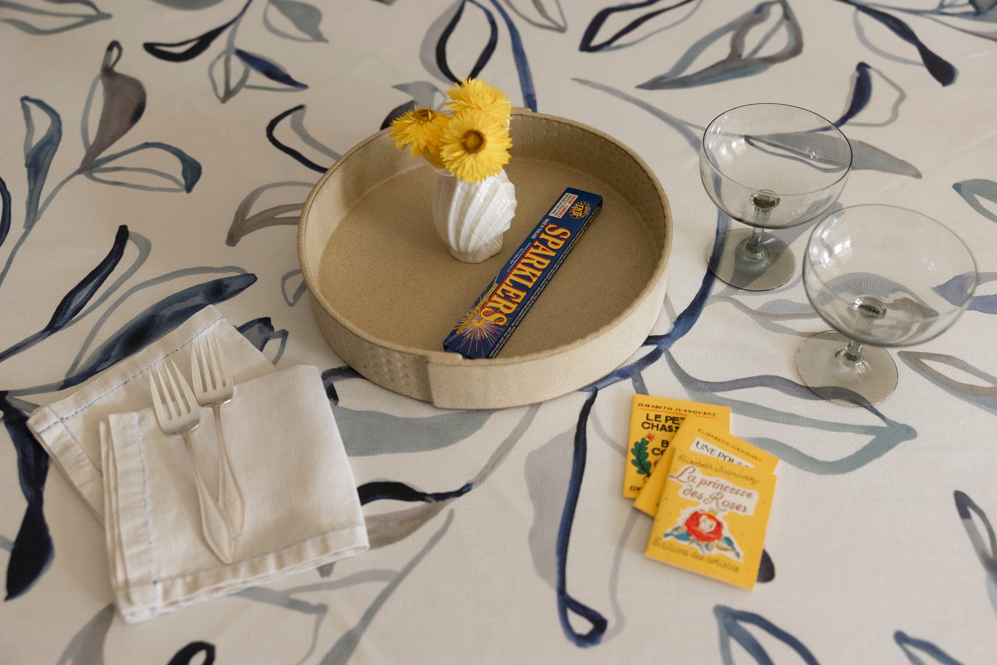 Table setting with a decorative plate, napkin, and small items on a patterned tablecloth.