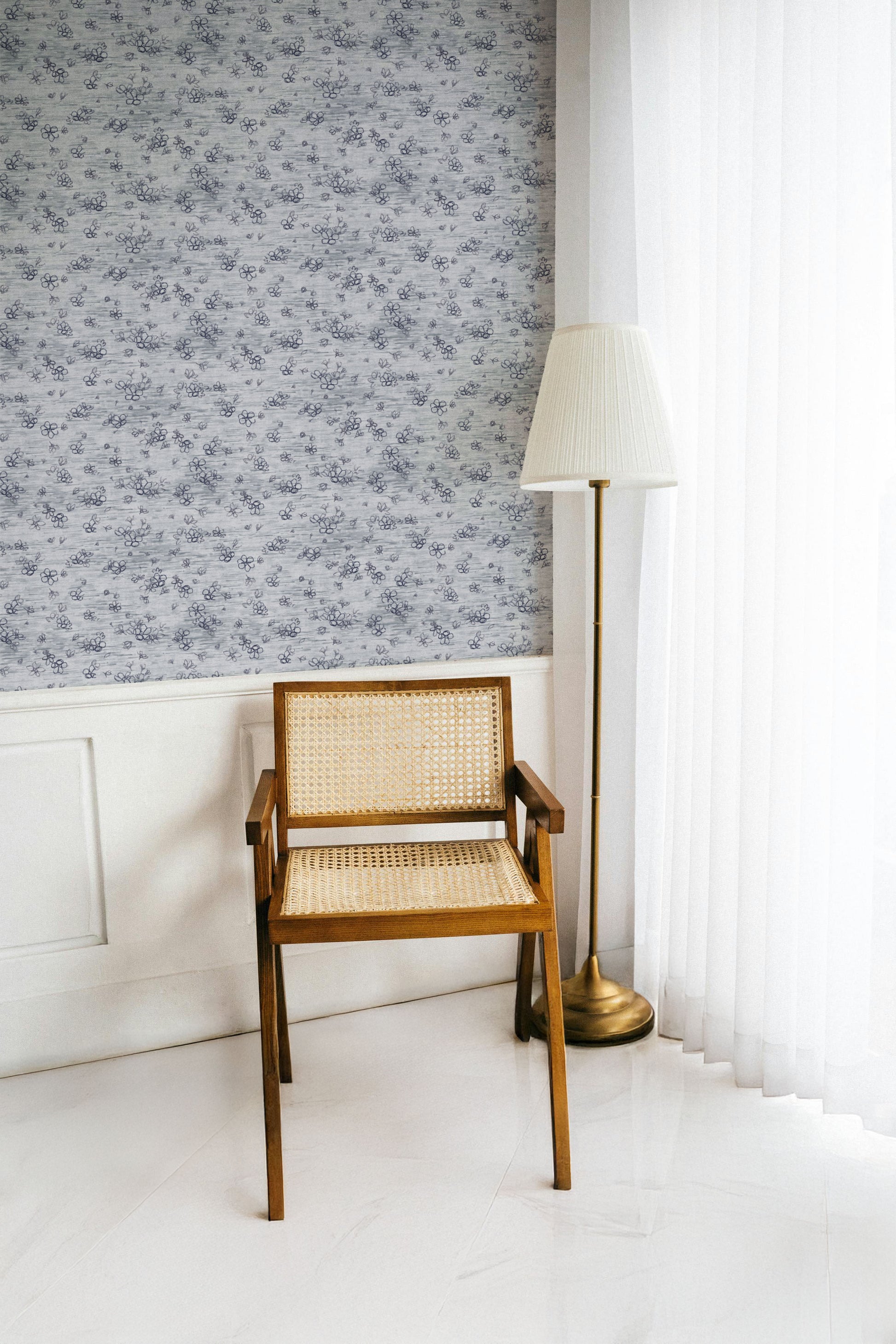 Wooden chair with woven backrest against a wall with floral wallpaper