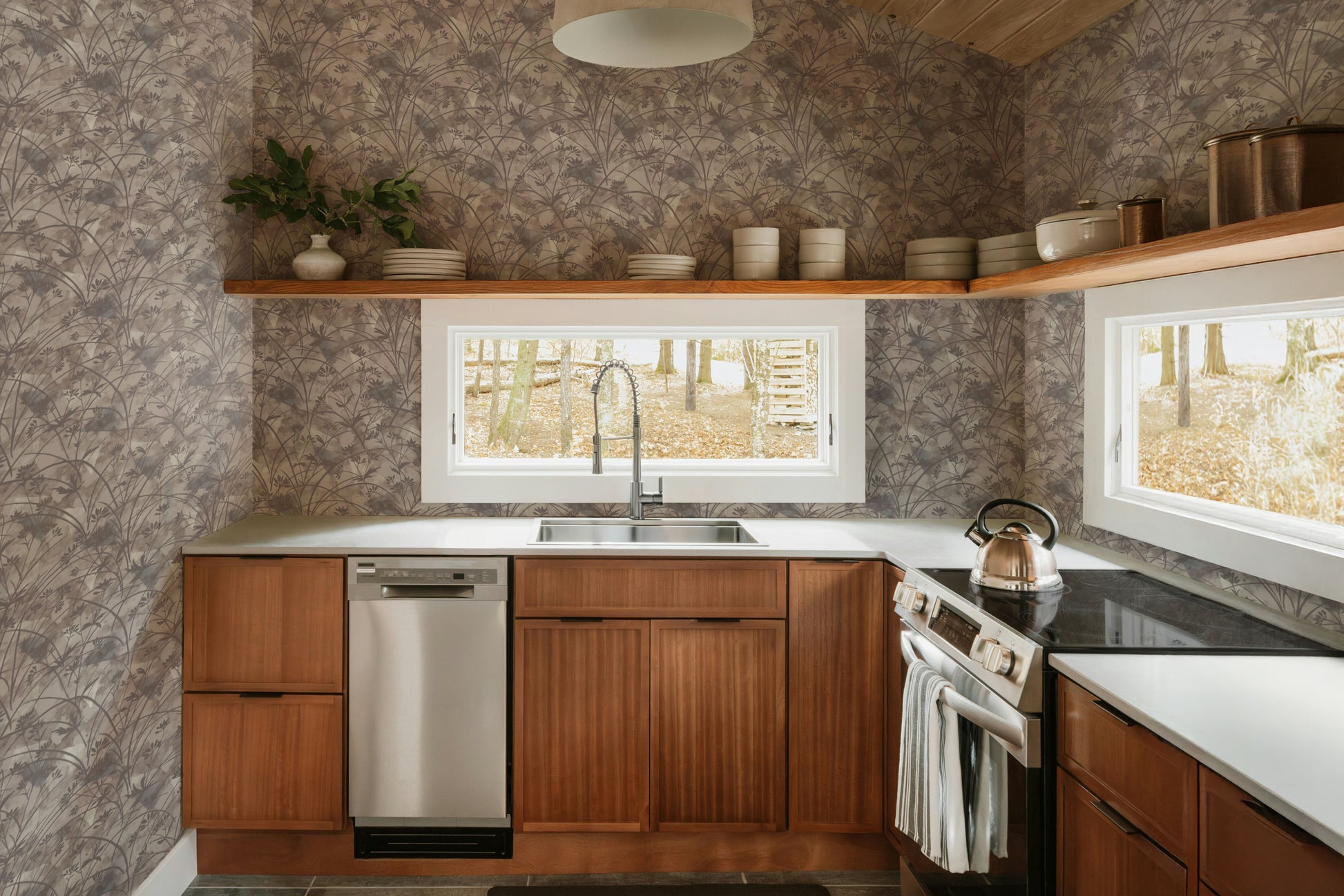 Modern kitchen with wooden cabinets, stainless steel appliances, and a wallpaper wall.