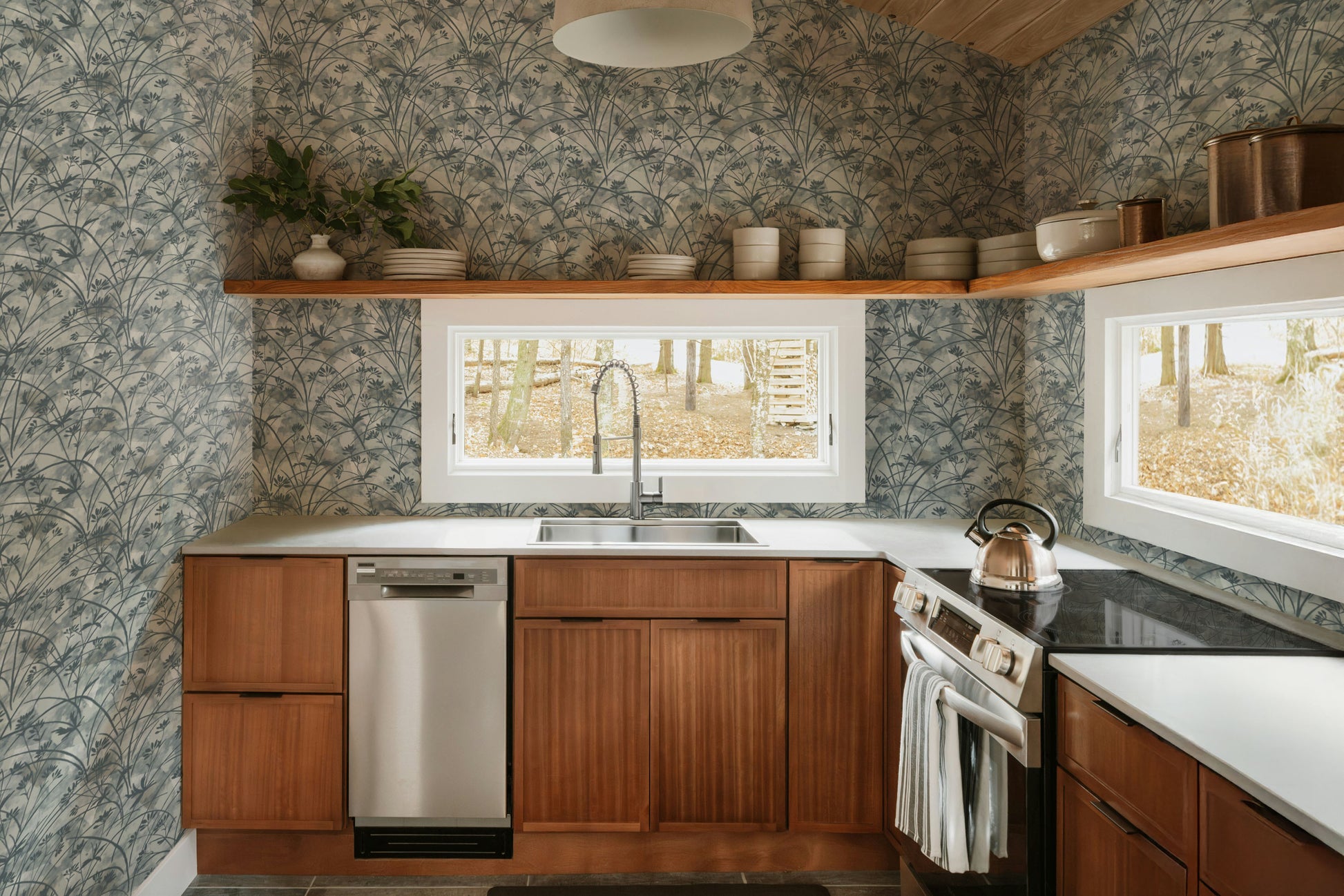Modern kitchen with wooden cabinets, stainless steel appliances, and a window view.