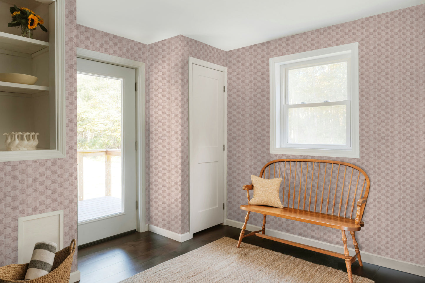 Room with pink patterned wallpaper, wooden bench, and a door leading outside.