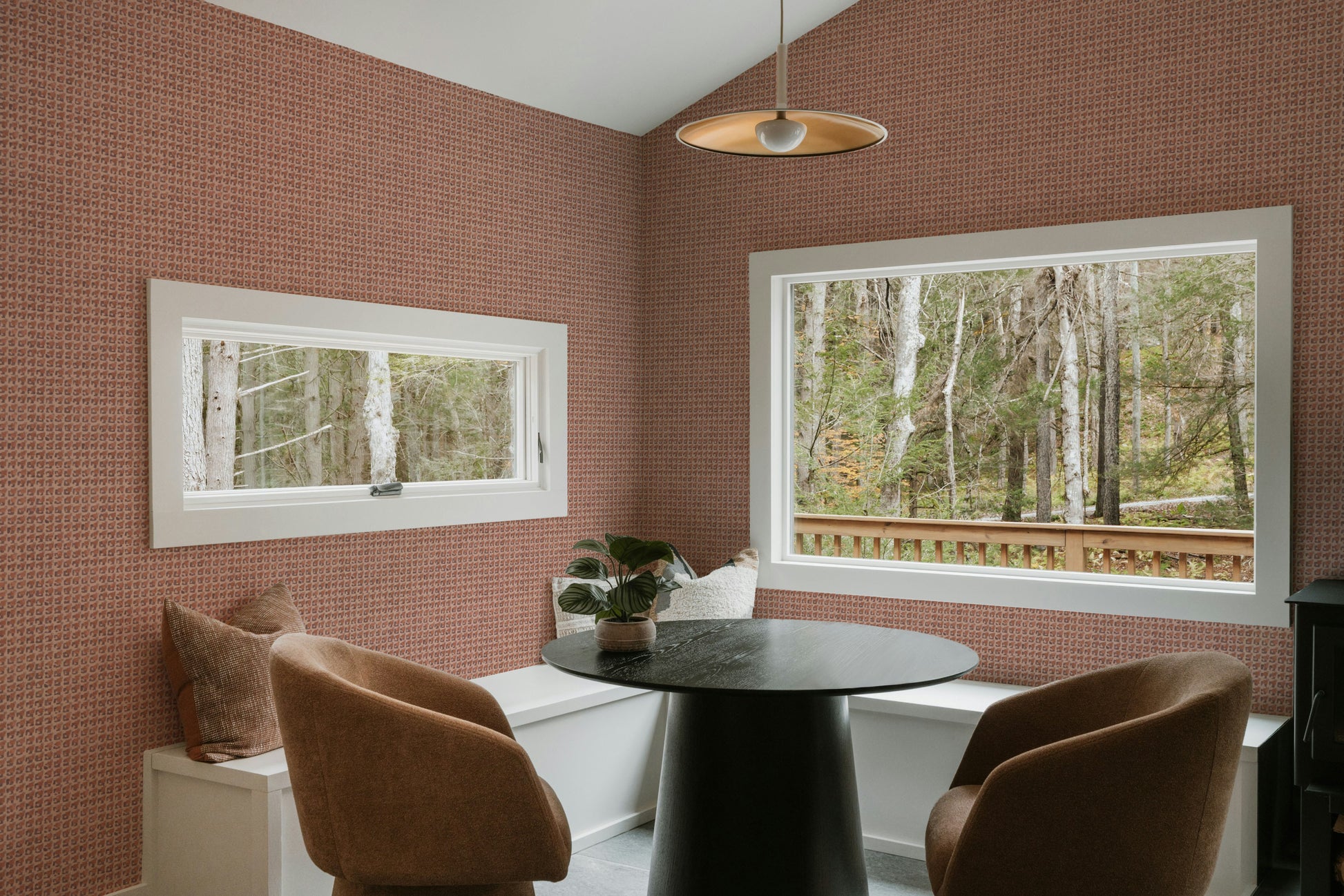 Dining room with pink walls, a round table, and brown chairs.