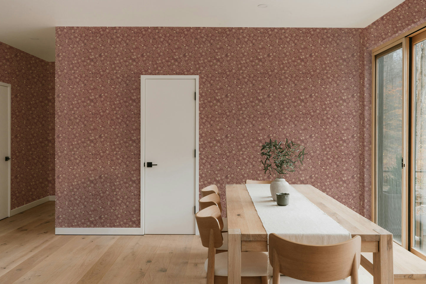 Dining area with wooden table and chairs against a patterned wall.
