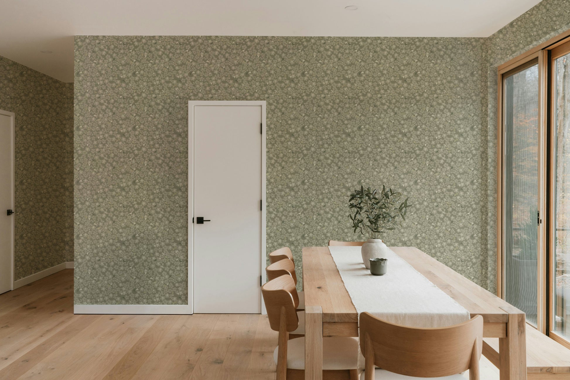 Dining area with wooden table and chairs against a patterned wall.